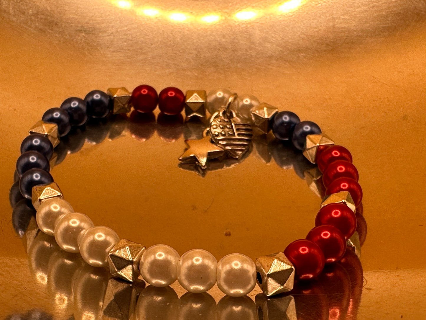 Patriotic Stretch Bracelet with Red, White and Blue beads with silver tone spacer beads. Features flag/heart and star charms.