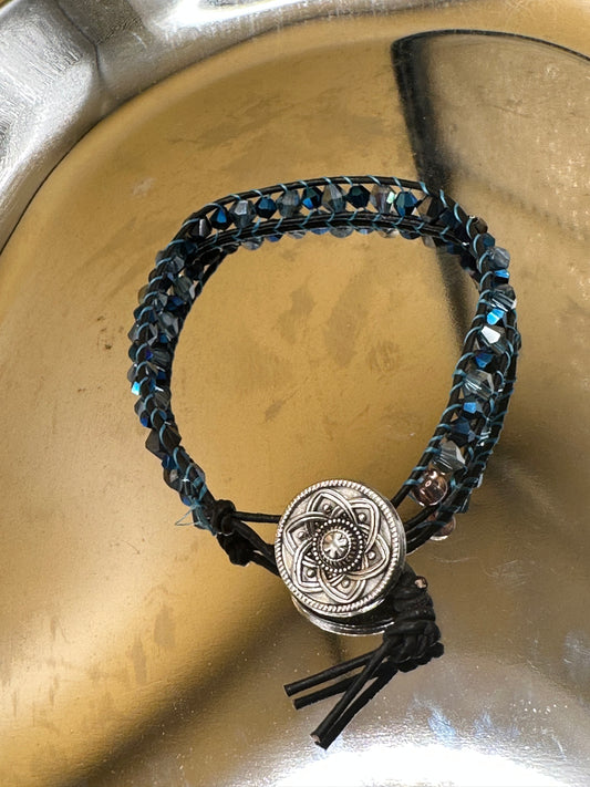 Bicone blue weaved, beaded leather bracelet with silver-toned flower button closure.