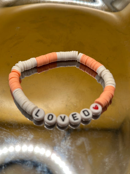 White and peach Heishi stretch Bracelet with "Loved" black and white round beads.