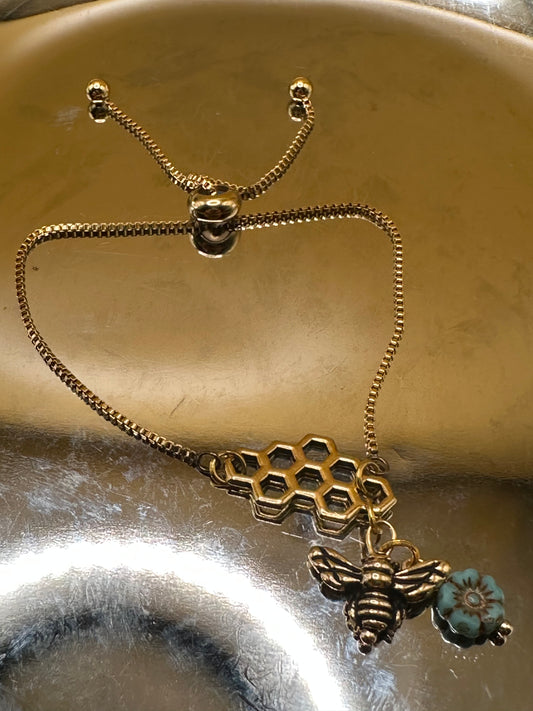 Gold toned adjustable bracelet with honeycomb focal  with bee charm with turquoise flower.